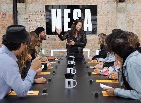 A Mesa leader presenting to a team gathered around the table