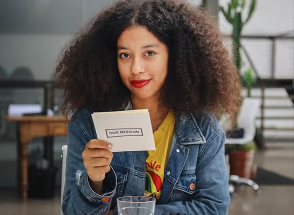 A Mesa participant holding a card that reads Our Mission